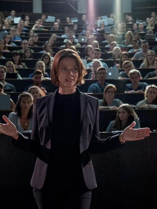 Die Schauspielerin Jessica Schwarz steht in der Rolle der Medizinprofessorin Lorenz in einem Hörsaal vor Studierenden.