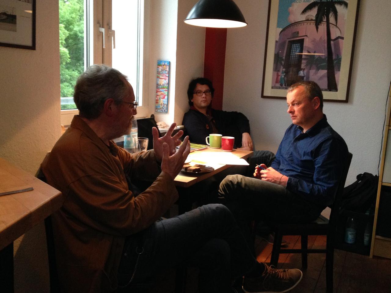 Interview am Küchentisch: Berndt A. Skott (l.) und Heiko Sakurai (Mitte hinten) im Gespräch mit DLF-Redakteur Jörg-Christian Schillmöller