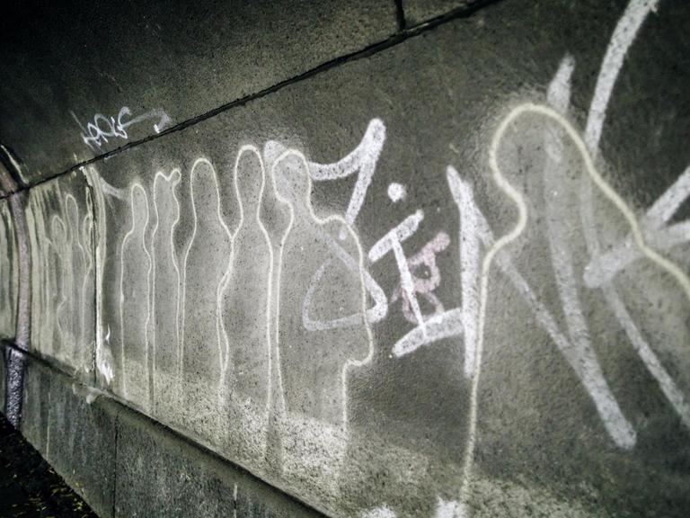 Auf dem Gelände des Loveparade-Unglücks erinnern Menschenumrisse an der Wand an die Vorfälle.