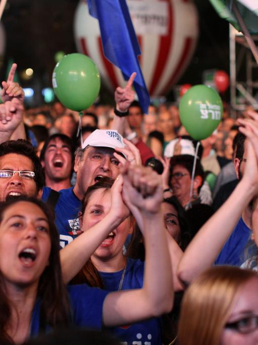 Eine Menschenmenge mit grünen Luftballons und israelischen Flaggen.