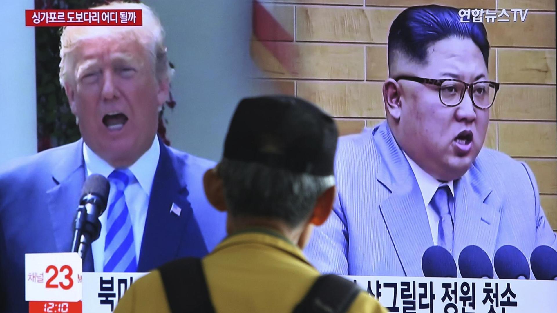 Das Bild zeigt einen Fernsehbildschirm. Auf dem sind die Staatschefs von den Ländern USA und Nord-Korea zu sehen.