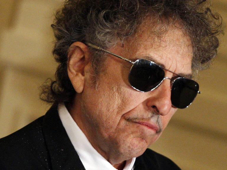 Der Musiker Bob Dylan mit schwarzer Sonnenbrille, aufgenommen bei einer Zeremonie im Weißen Haus in Washington 2012, bei der Dylan eine Friedensmedaille erhielt.