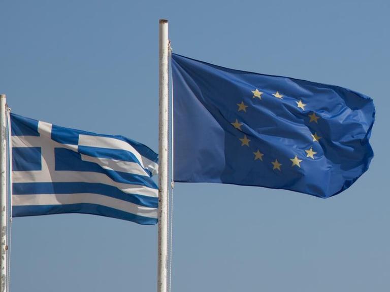 EU-Flagge und Griechenland-Flagge vor blauem Himmel
