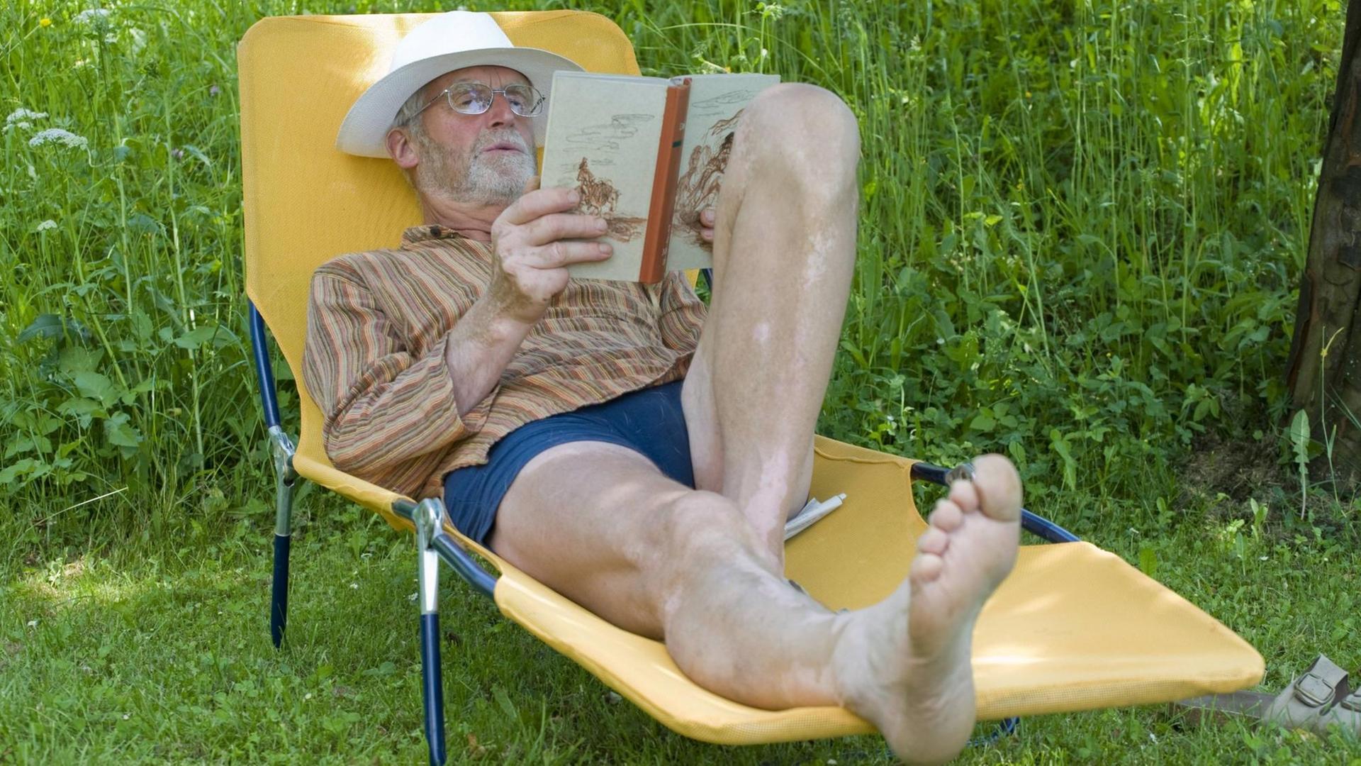 Ein Mann liegt auf einer Liege und liest ein Buch