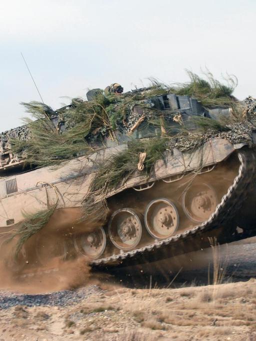 Ein Kampfpanzer vom Typ Leopard 2 in voller Fahrt auf einem Testgelände.