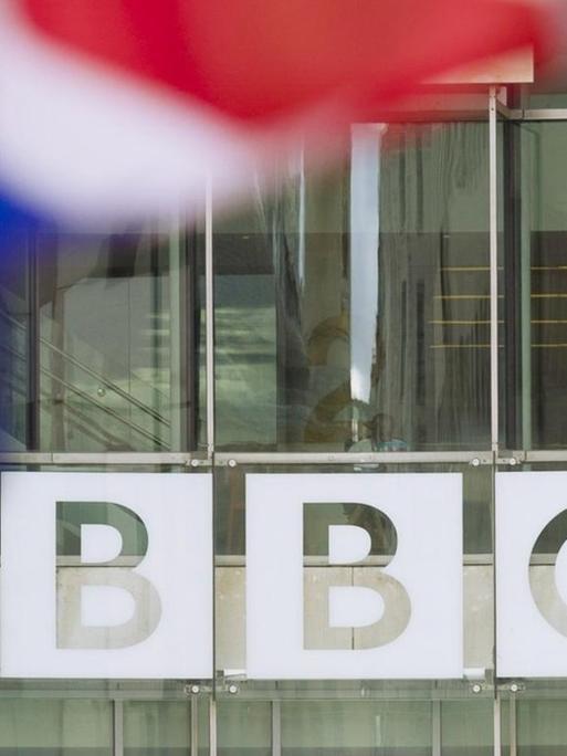 Eine Flagge von Großbritanien weht vor dem Schriftzug des Senders BBC