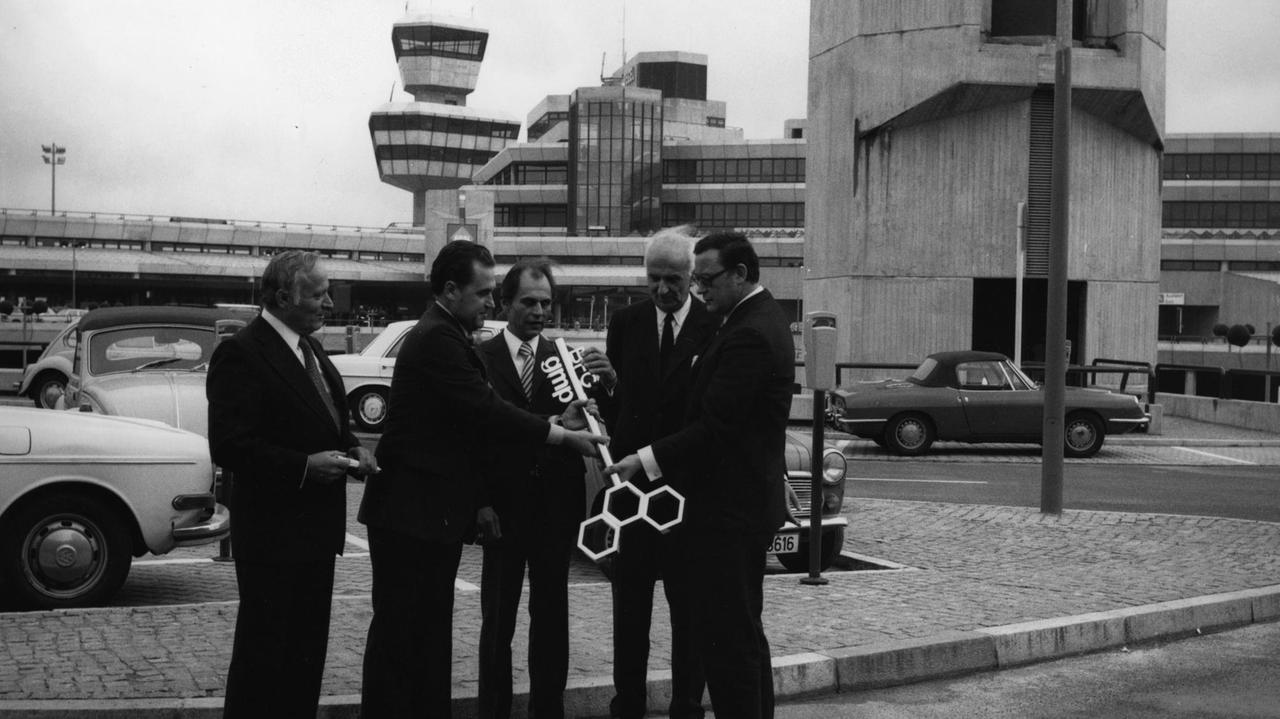 Der regierende Bürgermeister Klaus Schütz und seine Gäste posieren vor dem Tegeler Flughafen mit einem riesigen Schlüssel.