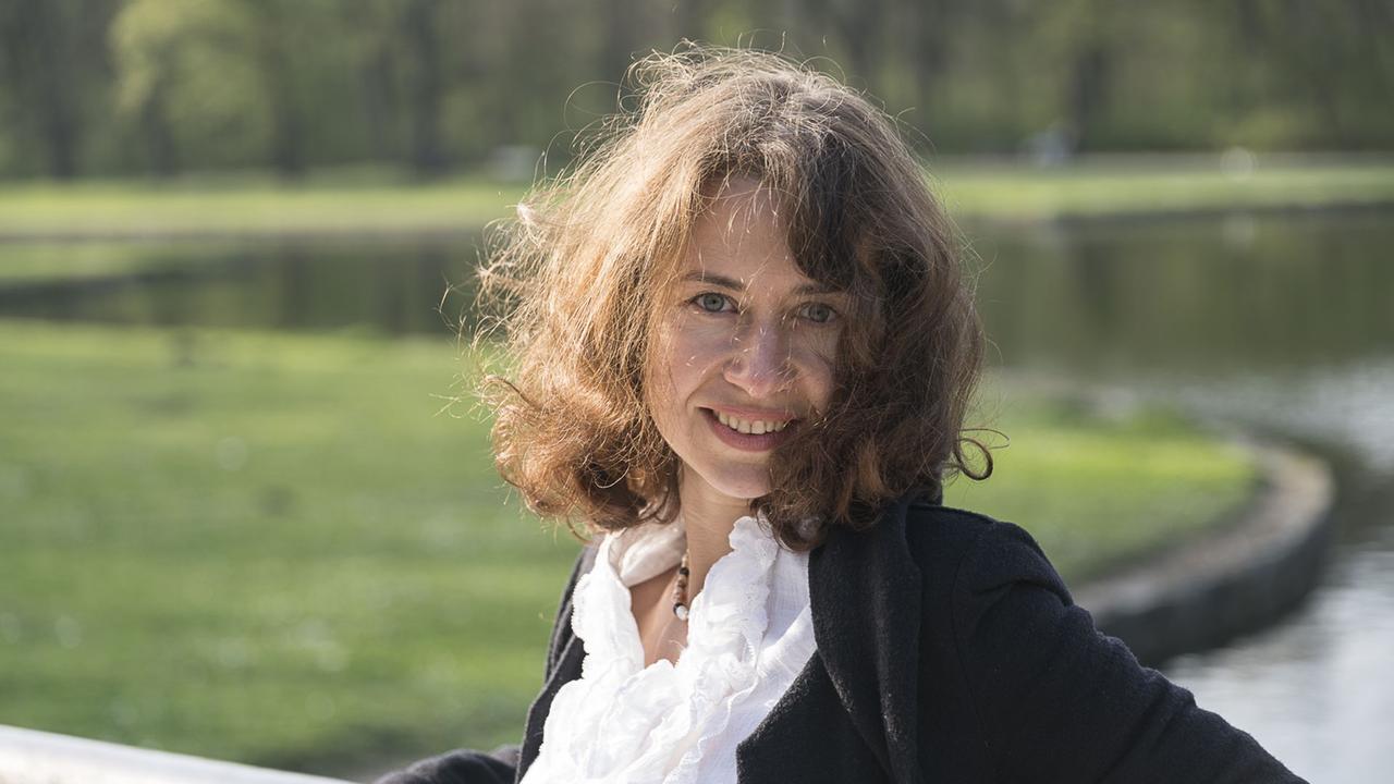 Die Pianistin Anna Zassimova steht auf einer Brücke im Park