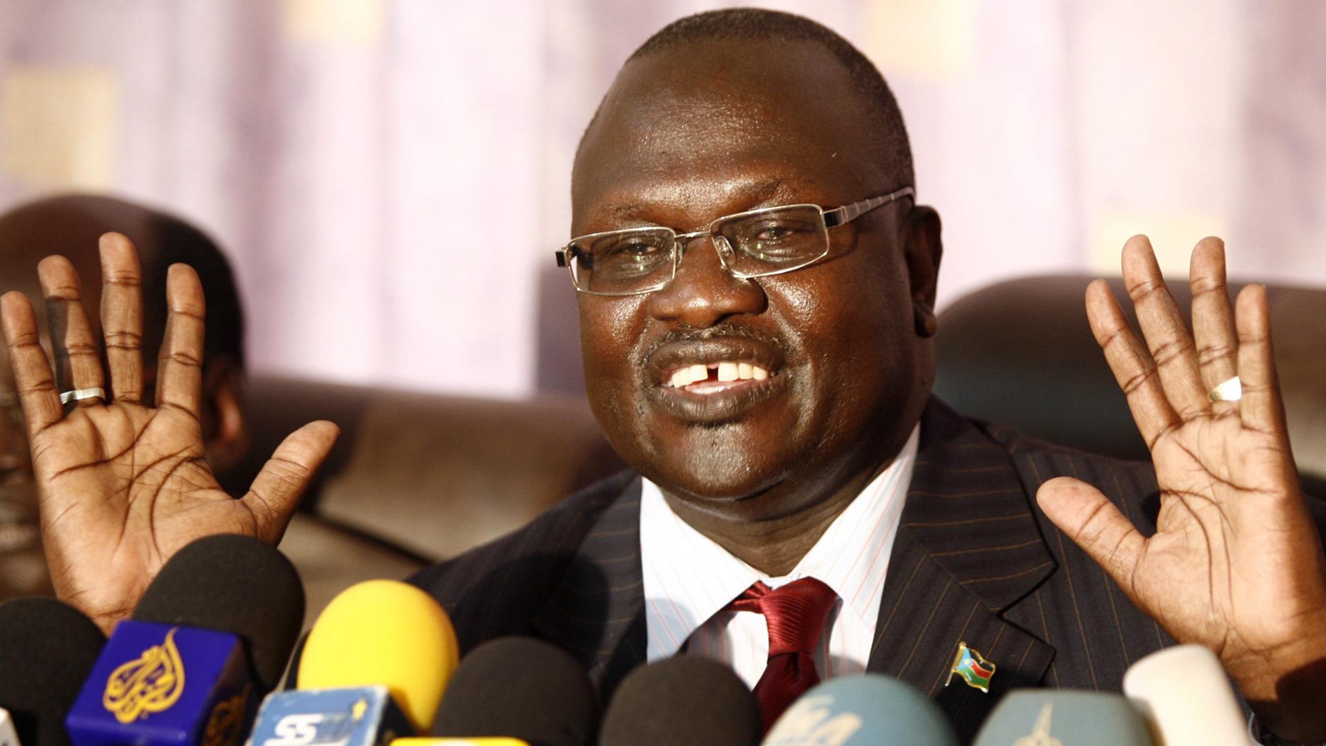 Der südsudanesische Rebellenführer steht hinter zahlreichen Mikrofonen.