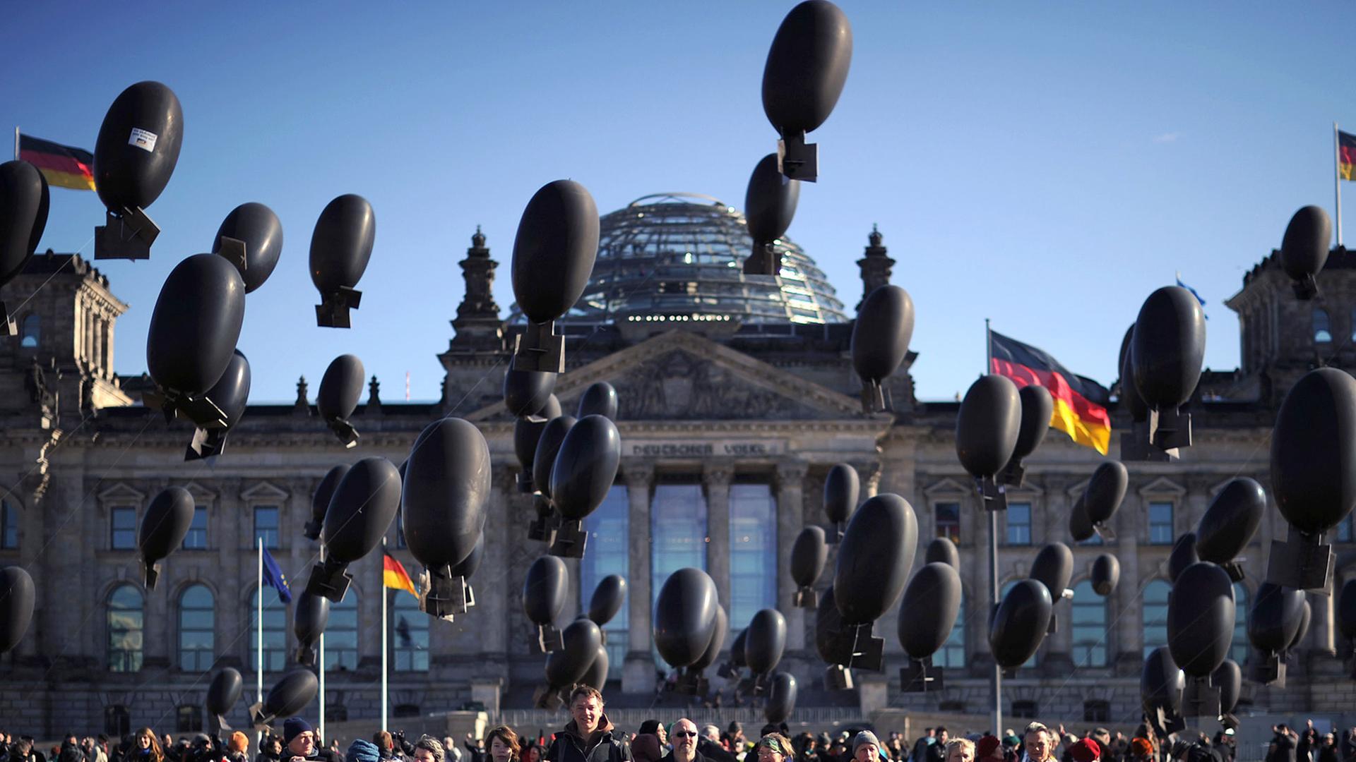Aktivisten demonstrieren vor dem Reichstag in Berlin gegen deutsche Rüstungsexporte. Mit 100 bombenähnlichen, mit Helium gefüllten Ballons, soll bei der Kunstaktion die ausgehenden Rüstungsexporte symbolisiert werden.