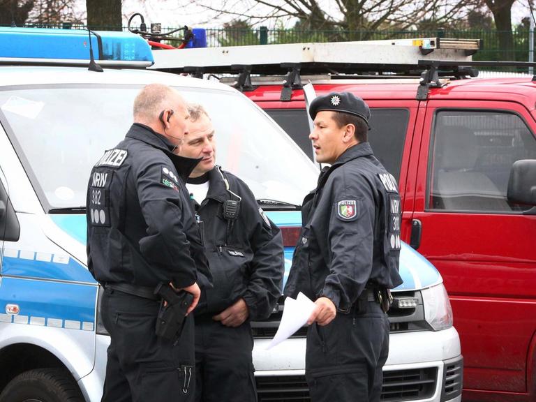 Polizisten stehen vor Einsatzfahrzeugen in Alsdorf.