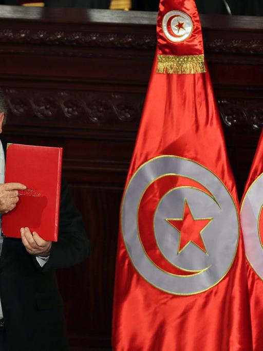 epa04044444 Constituent Assembly Speaker Mustapha Ben Jaafar holds a the new constitution during the official ceremony of signing of the new Constitution, at the Tunisian Constituent Assembly in Tunis, Tunisia, 27 January 2014. The Constitution was signed