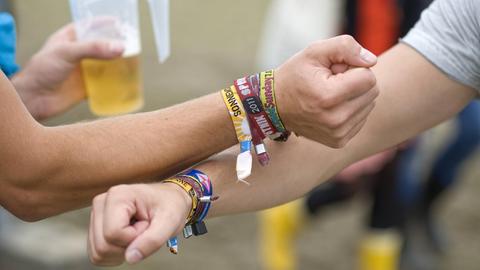 Zwei männliche Besucher des SonneMondSterne Musikfestivals an der Bleilochtalsperre im thüringischen Saalburg zeigen ihre Unterarme mit Bändchen von diversen Musikfestivals, die sie in diesem Jahr besucht haben.