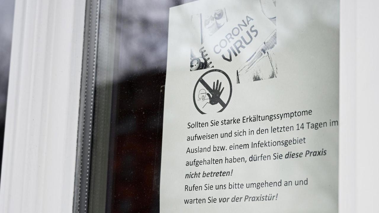 Ein Informationsblatt zum Umgang mit möglichen Corona-Infizierten hängt im Fenster einer Arztpraxis in Erfurt.