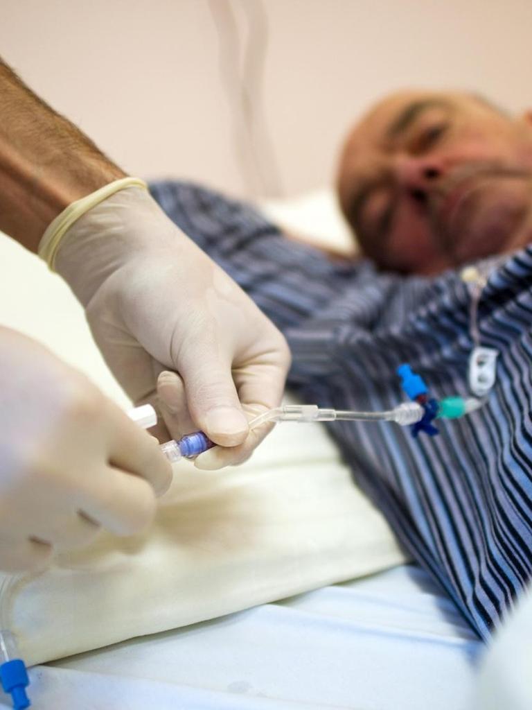 Ein Krankenpfleger wechselt in einer Krebsstation des Universitätsklinikum Carl Gustav Carus (UCC) in Dresden eine Kanüle zur künstlichen Ernährung des an Darmkrebs erkrankten Patienten.