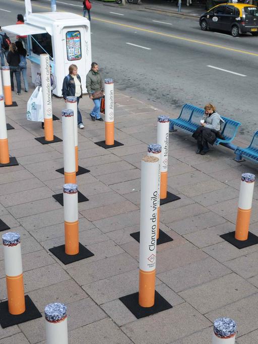 Eine Installation aus überdimensionalen Zigaretten steht auf einem belebten Platz.