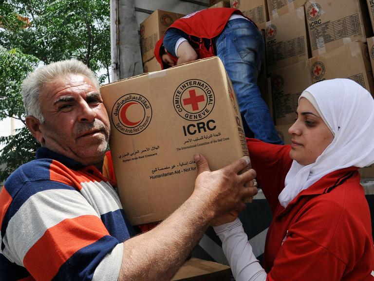 Einwohner nehmen in Moadamiyeh, einem Vorort von Damaskus, Hilfsgüter vom Roten Kreuz entgegen, aufgenommen 2015
