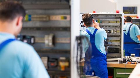 Drei junge Flüchtlinge arbeiten im Ausbildungszentrum der Siemens Professional Education an der Verdrahtung eines Schaltschranks.