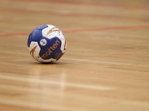 Ein Handball liegt auf den Hallenboden.