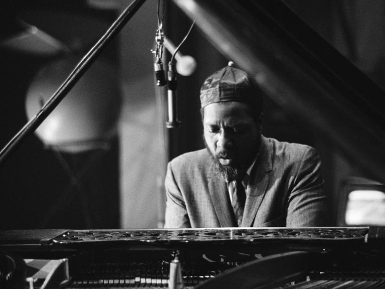 Schwarz-weiß-Foto des US-amerikanischen Jazzpianisten und Komponisten Thelonius Monk, der an einem offenen Flügel spielt.
