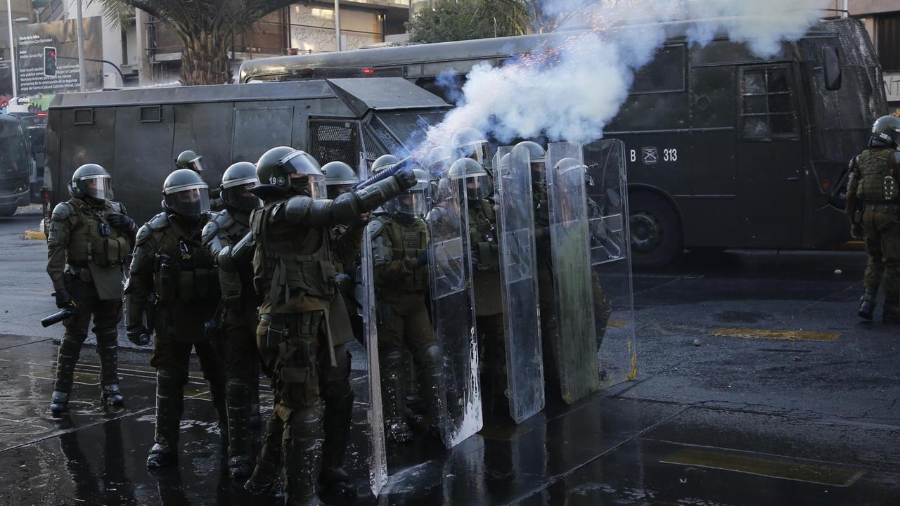 Eine Gruppe von chilenische Bereitschaftspolizisten schießen Tränengas auf Demonstranten.