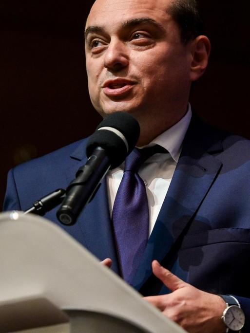 Basil Kerski steht an einem Rednerpult mit Mikrofon