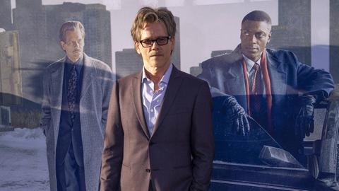 Kevin Bacon mit Sonnenbrille, steht vor einem Filmplakat von "City on a hill"