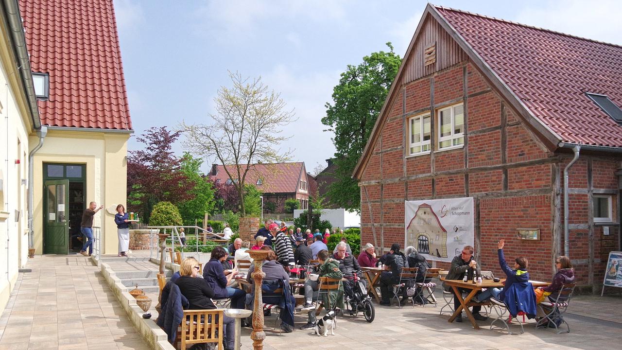 Ein ehemaliger umgebauter Bauernhof mit einem Café, in dem Menschen draußen sitzen