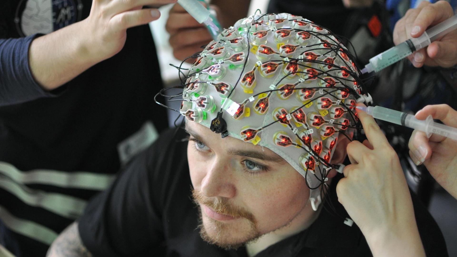 Ein Mann bekommt Elektroden an den Kopf gebracht