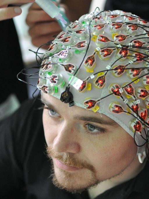 In den Gehirnströmen verbergen sich Muster. Um die für das Computersystem erkennbar zu machen, müssen 129 Elektroden einzeln gegelt und an der Kopfhaut angebracht werden