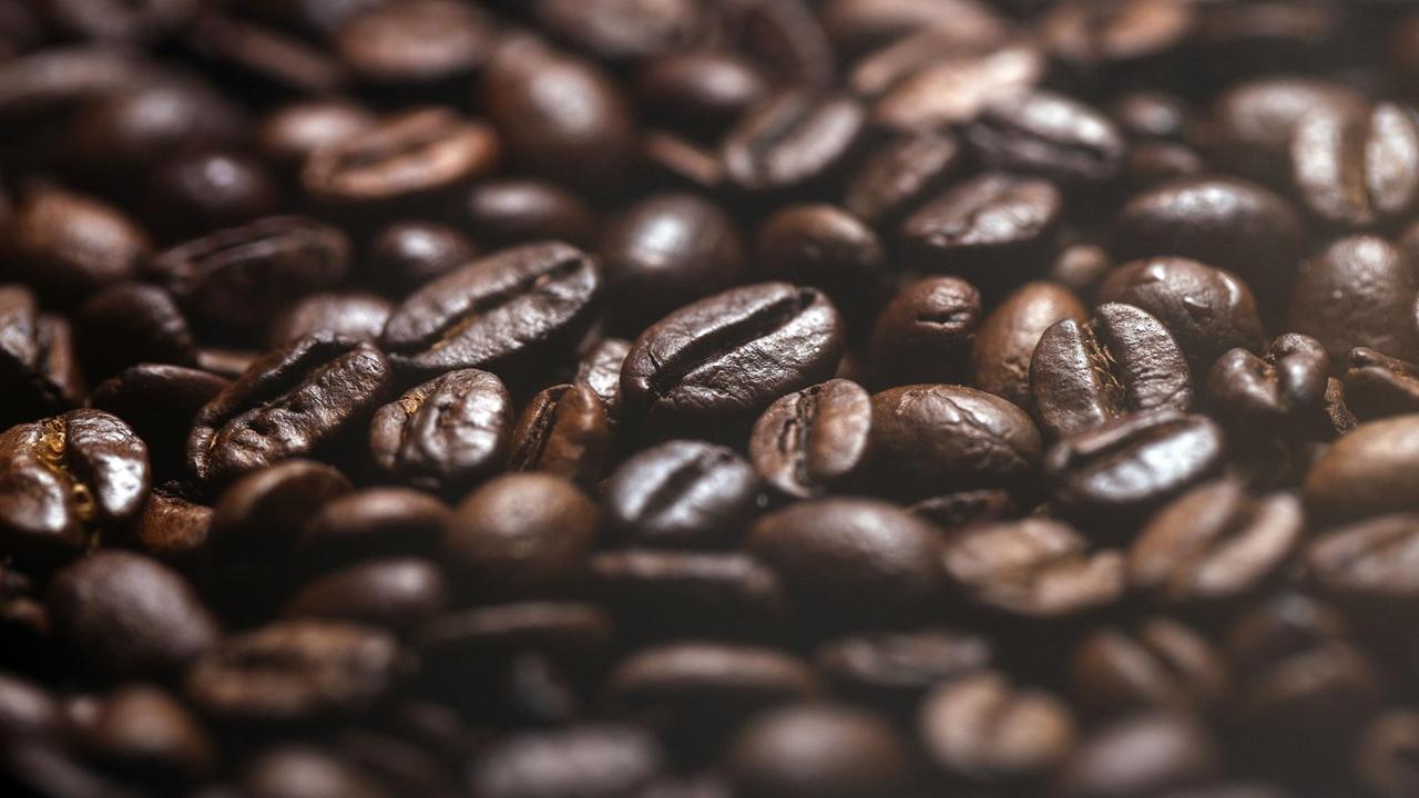 Das Bild zeigt eine Nahaufnahme von vielen Kaffeebohnen.