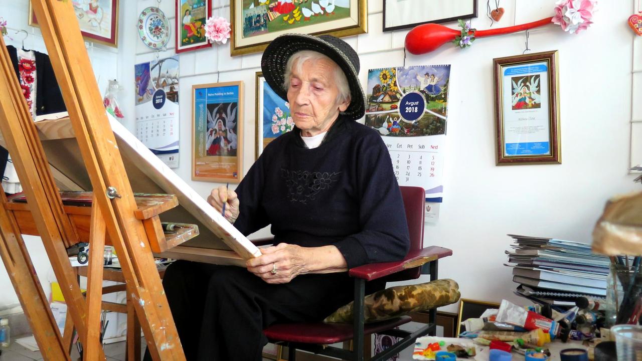 Die Malerin Alzbeta Chizikova sitzt vor einer Staffelei und malt