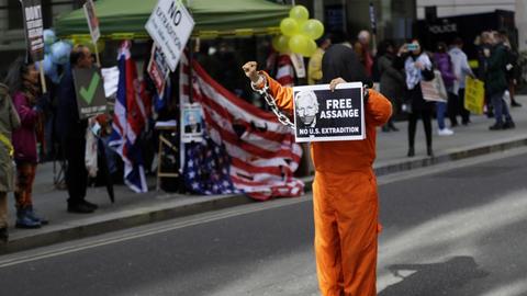 Ein maskierter Demonstrant hat sich als Gefängnisinsasse verkleidet und hält am 1. Oktober 2020 in London ein Schild mit dem Konterfei von julian Assange und der Aufschrift "Free Assange" in der Hand.