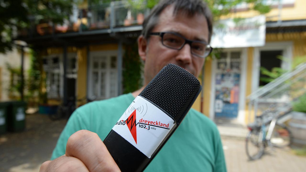 Der Pressesprecher Andreas Reimann von Radio Dreyeckland hält am 18.07.2013 vor dem Studio von Radio Dreyeckland in Freiburg (Baden-Württemberg) ein Mikrofon in der Hand. 