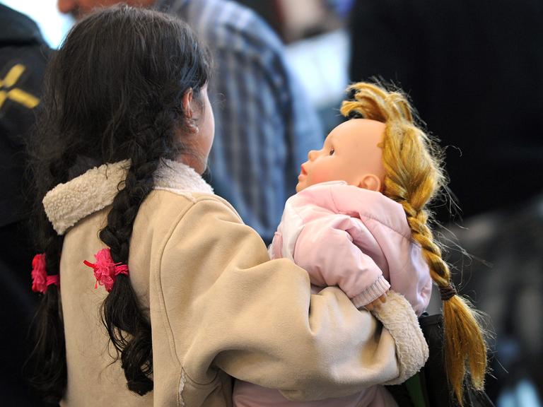 Ein Mädchen hält eine Puppe im Arm.