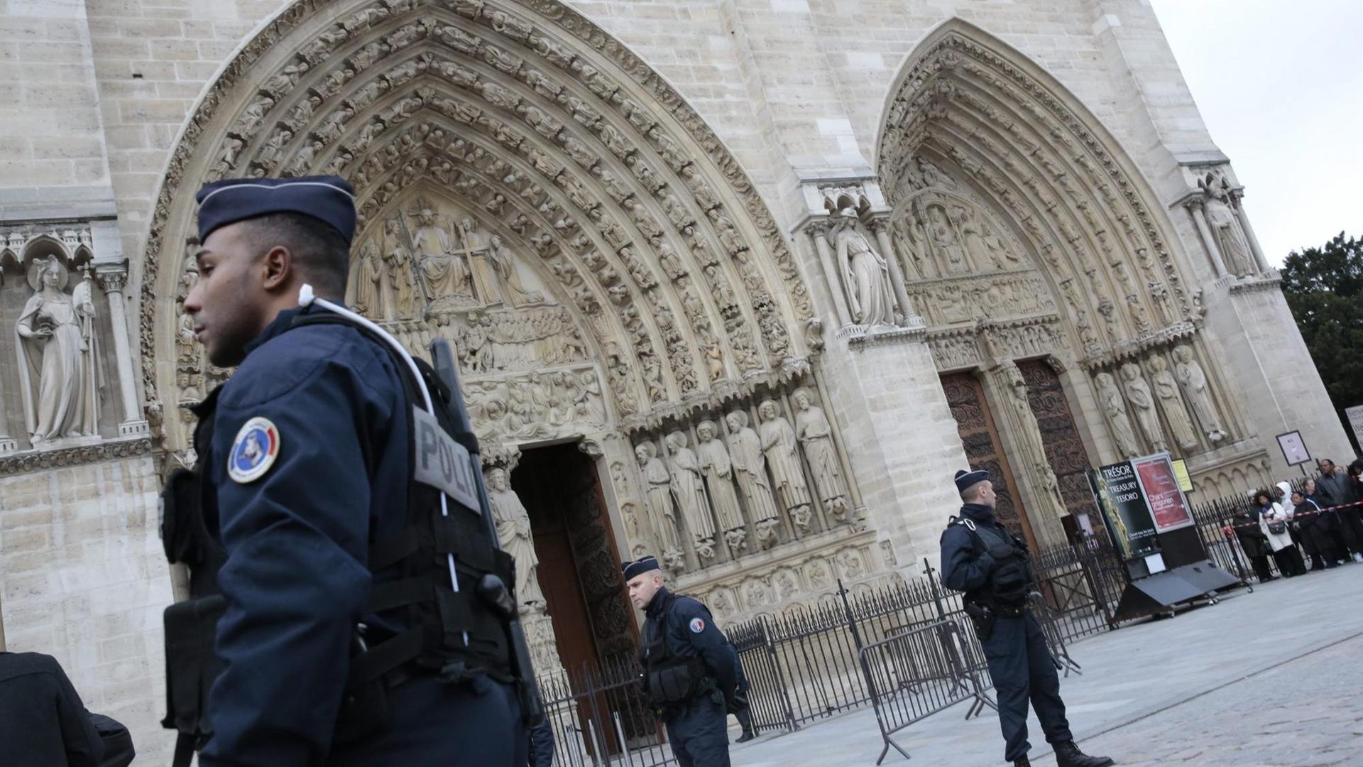 Polizisten stehen vor dem Hauptportal der Kirche Notre Dame in Paris