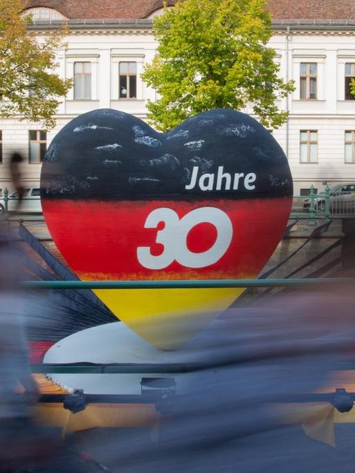 Passanten gehen an einem schwarz-rot-goldenen Herz mit der Aufschrift "30 Jahre" vorbei. Potsdam als Brandenburger Landeshauptstadt war in diesem Jahr Gastgeber der zentralen Feierlichkeiten zum Tag der Deutschen Einheit.