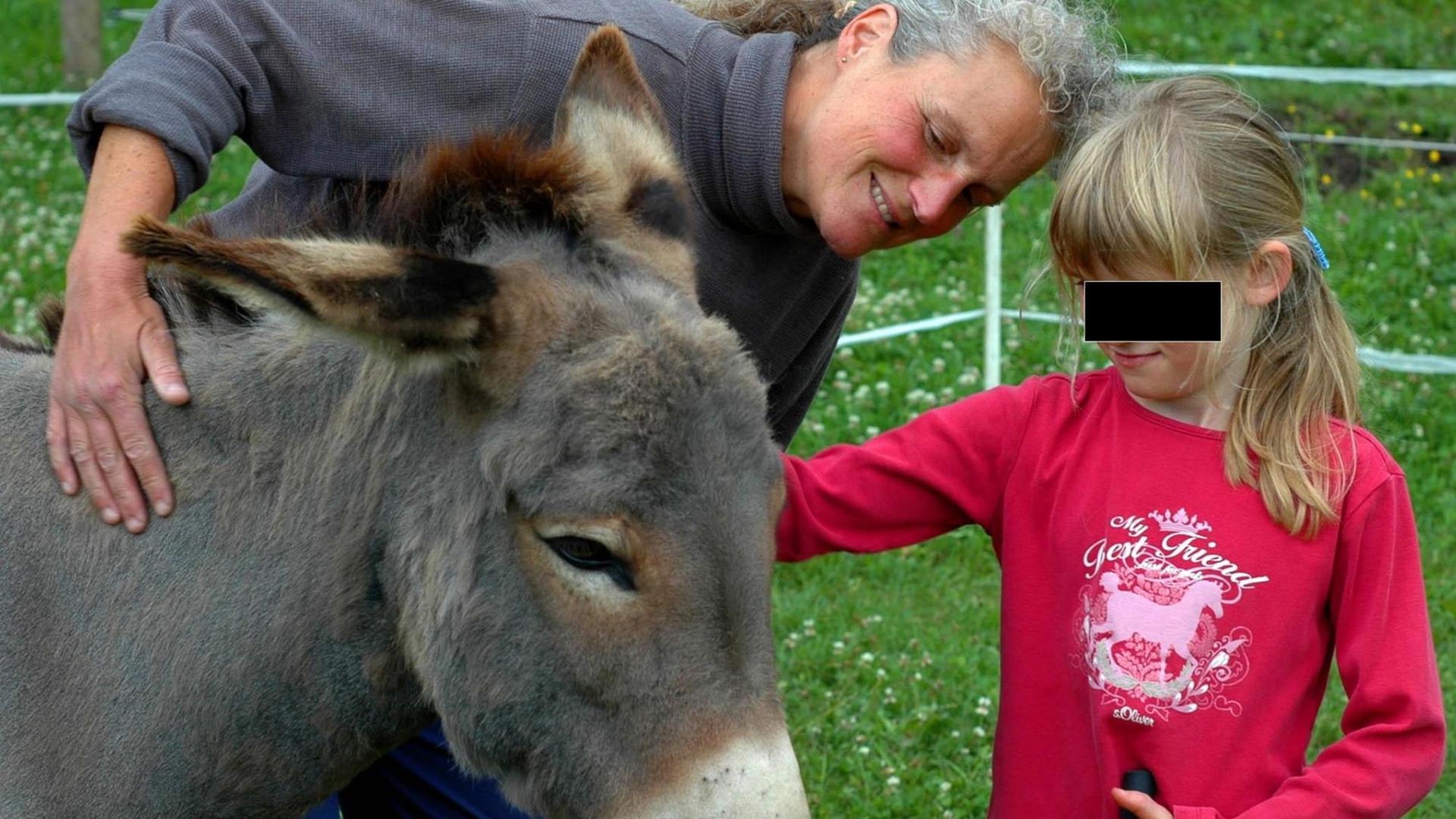 Ein sieben Jahre altes Mädchen streichelt bei der Tiergestützen Therapie einen Esel.