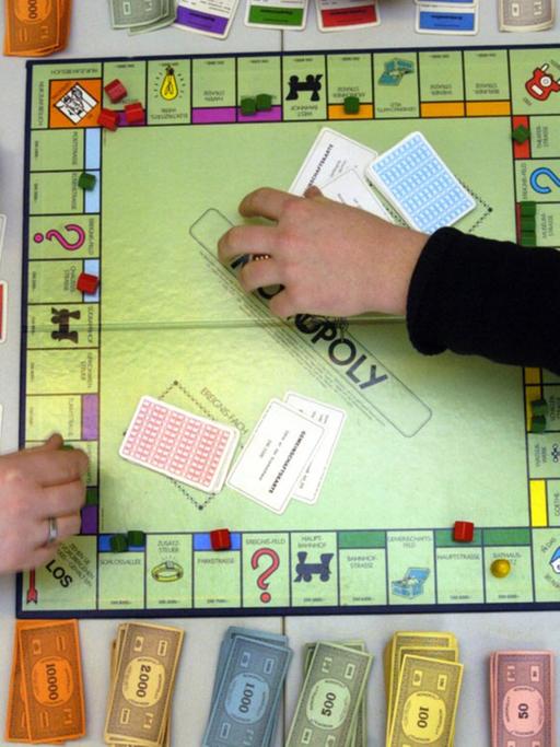 Hände an einem Monopoly-Spielbrett