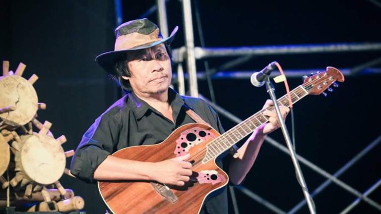 Der Musiker Jo Rangsan spielt auf einer Gitarre.