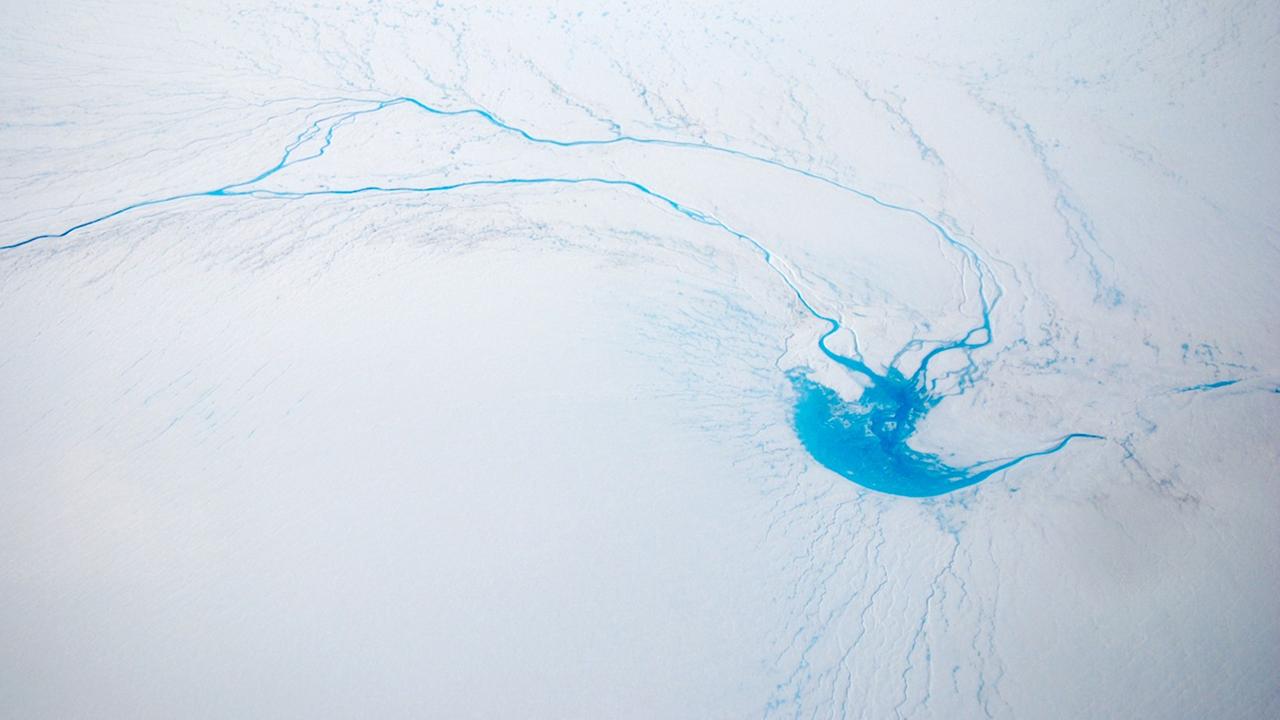 Das Foto zeigt einen einen Fluss, der im Eis eines Gletschers auf Grönland verschwindet.