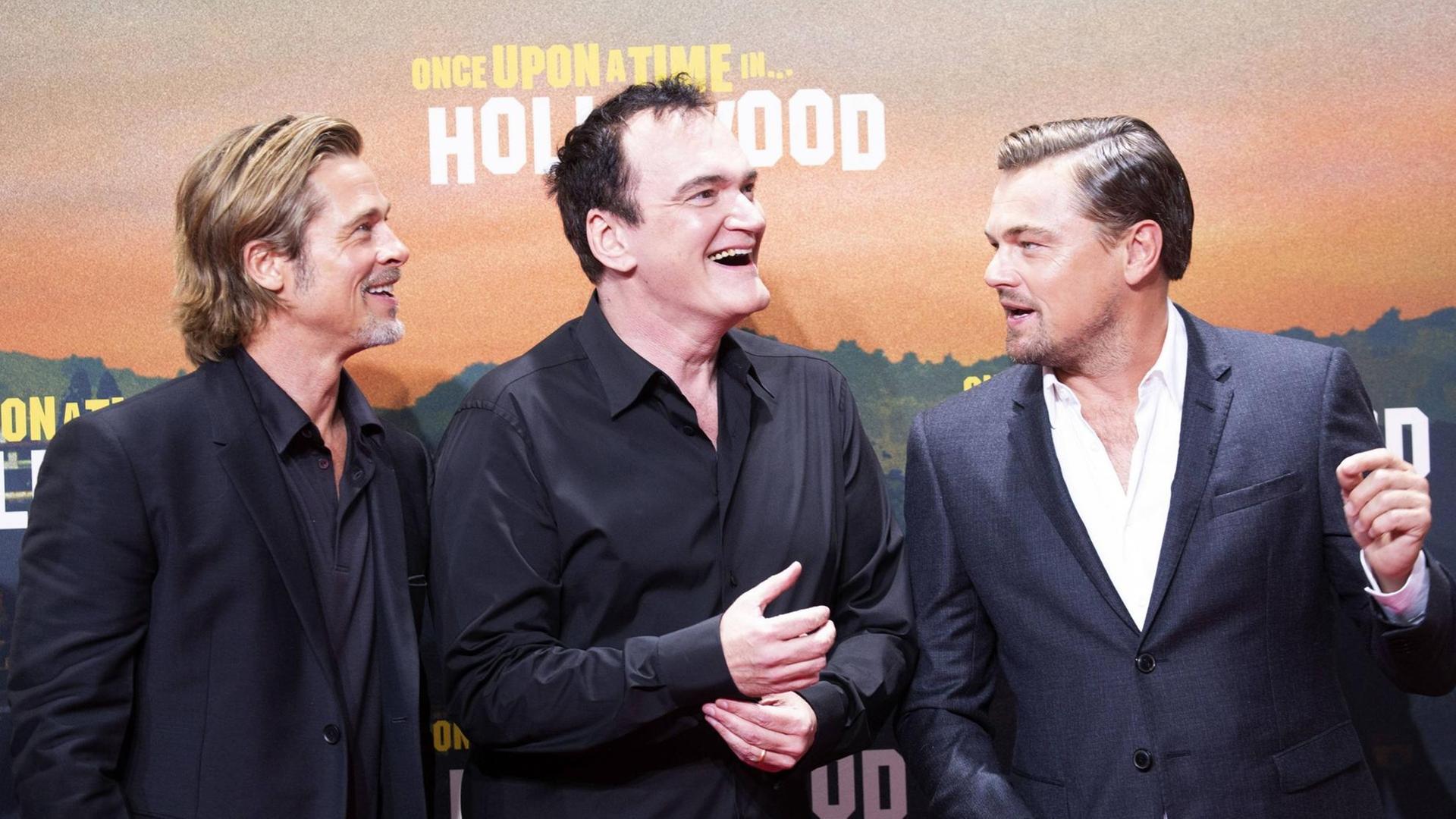 Die Schauspieler Brad Pitt (li) und Leonardo DiCaprio mit dem Regisseur Quentin Tarantino (Mitte) bei der Premiere des Kinofilms Once "Upon a Time in... Hollywood" vor einem Plakat zum Film am Potsdamer Platz in Berlin am 01.08.2019
