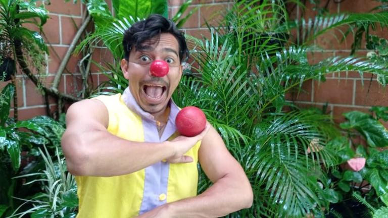Porträt von Eduardo Barahona mit roter Clownsnase, der einen roten Ball balanciert.