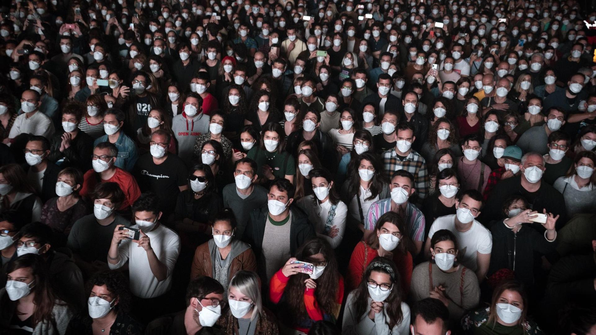 Menschen mit Mund-Nasen-Bedeckung besuchen ein Musikkonzert. 