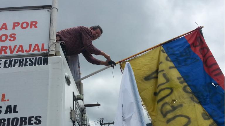 Ein Mann auf einem Protestwagen schwenkt bei einem Friedensmarsch in Bogotá die kolumbianische Flagge