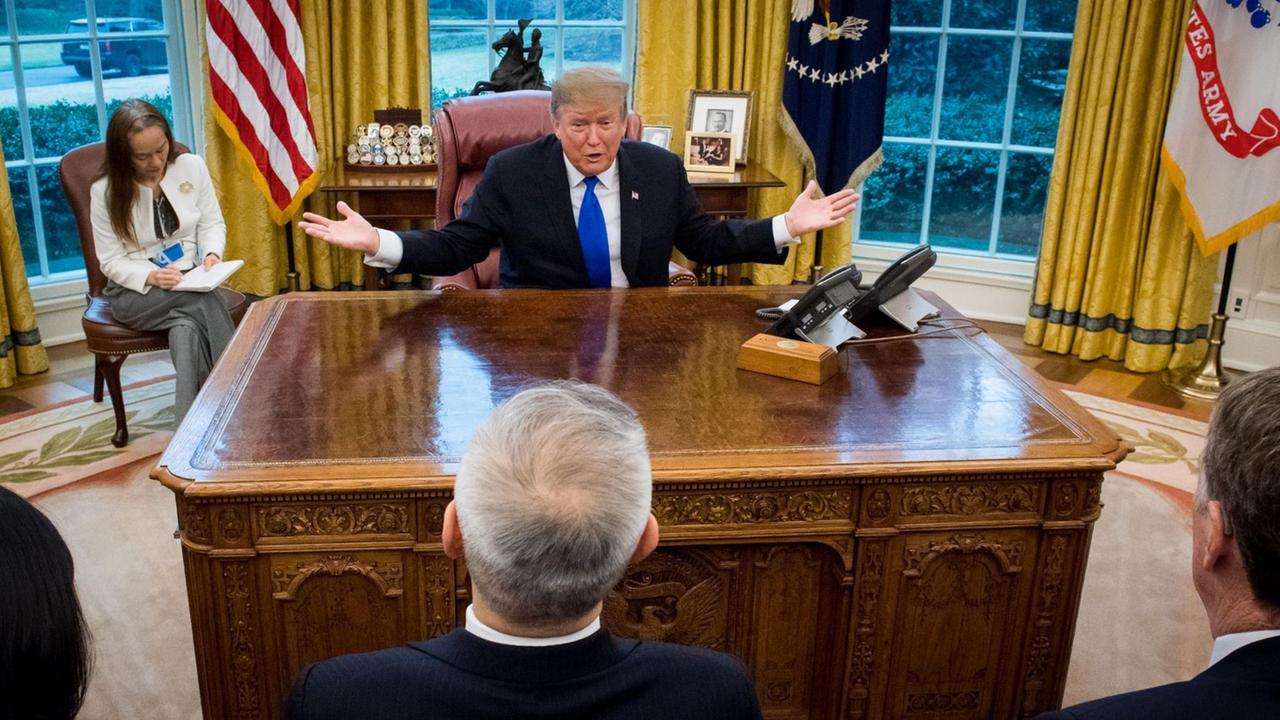 US-Präsident Donald Trump im Oval Office im Februar 2019. Trump sitzt an seinem Schreibtisch und vor ihm sitzen mehrere Menschen. 