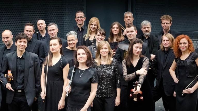 Die Ensemblemitglieder des Wrocław Baroque Orchestra stehen mit ihren Instrumenten dicht beieinander