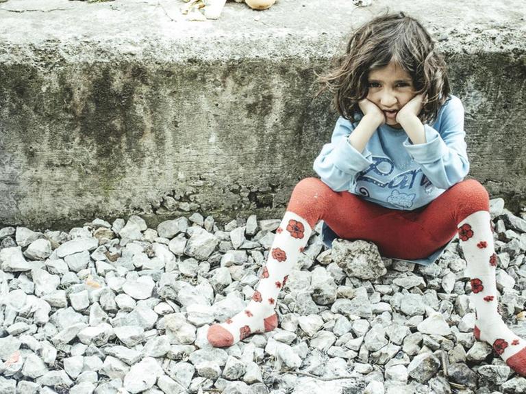 Ein Kind sitzt auf dem Bahnsteig im Bahnhof, Idomeni, Zentralmakedonien, Griechenland, Europa auf dem Boden.