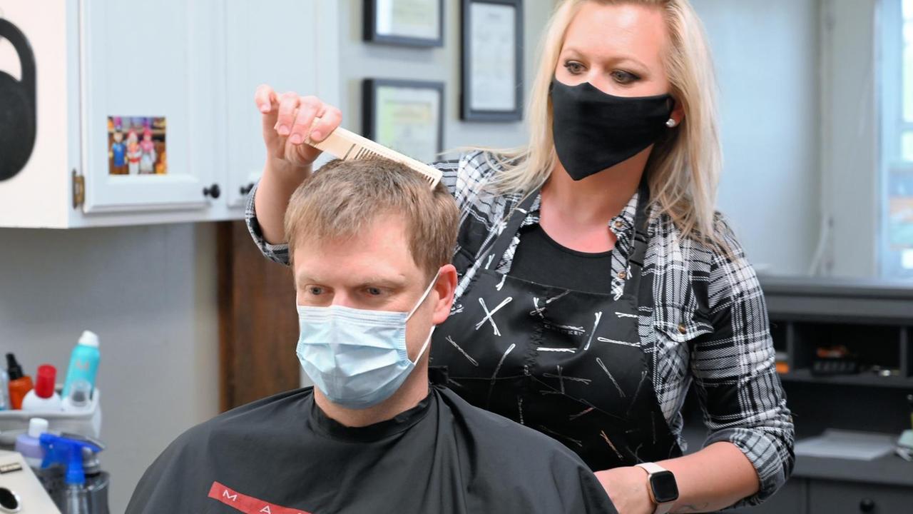 Ein Friseur mit Mundschutz schneidet einem Kunden die Haare - seit 4.Mai dürfen Friseure unter Hygieneauflagen wieder für Kunden öffnen