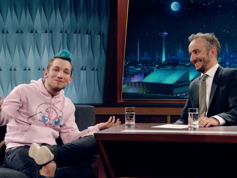 "NEO MAGAZIN ROYALE mit Jan Böhmermann - Sendung vom 13.06.19": Der Youtuber Rezo und Jan Böhmermann sitzen am Schreibtisch auf der Bühne im Fernsehstudio während der Sendung.